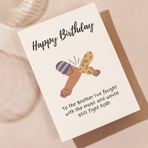 May include: A white birthday greeting card featuring the black text Happy Birthday at the top and an illustration of two arms performing an elbow bump. Below the illustration is the text To the Brother I've fought with the most and would still fight FOR!