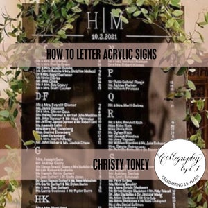 May include: Black acrylic wedding seating chart with white calligraphy. The sign includes the names of guests, initials, and the date. The text "HOW TO LETTER ACRYLIC SIGNS" is also visible. Greenery frames the top.