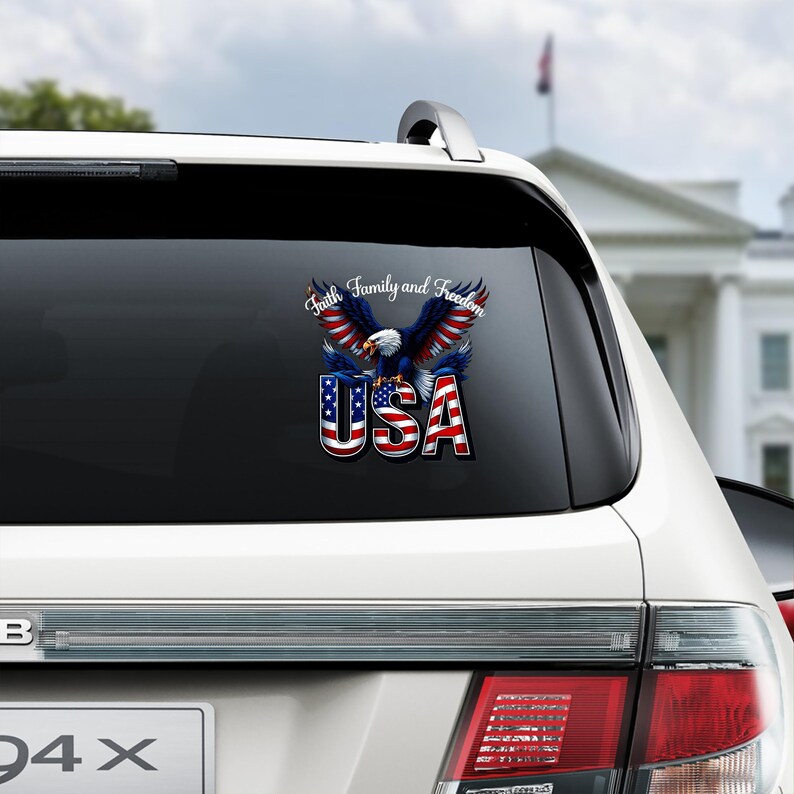 May include: A patriotic decal featuring a bald eagle with outstretched wings, colored in red, white, and blue. The word "USA" is prominently displayed below the eagle, with the text "Faith, Family, and Freedom" above. The decal is affixed to a car window.
