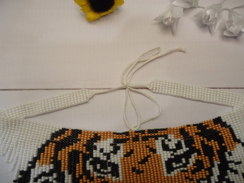 May include: A beaded tiger necklace with white fringe and a white string tie closure.