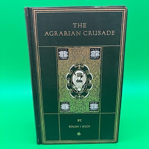 May include: A hardcover book titled "The Agrarian Crusade" by Solon J. Buck. The book has a dark green cover with gold lettering and decorative elements. The cover features the text "LVX ET VERITAS" and a crest.