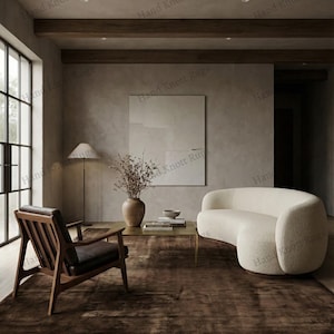 May include: A modern living room featuring a dark brown rug, a curved white sofa, and a wooden armchair with a leather seat. A coffee table with a vase of dried flowers and a lamp are also present.