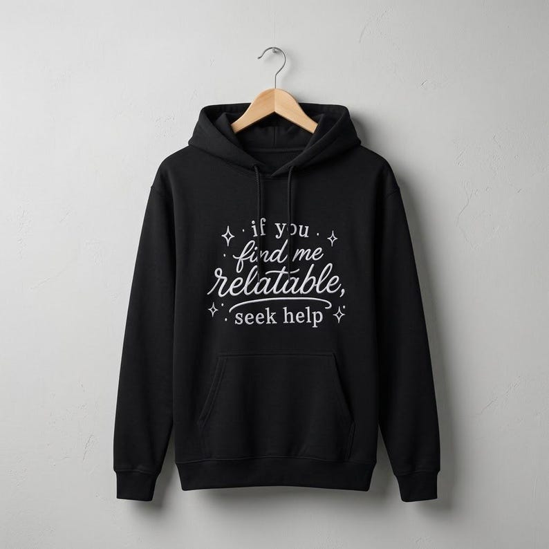 Pu&ograve; includere: Una felpa con cappuccio nera con la scritta bianca "if you find me relatable, seek help" circondata da piccole icone a forma di stella. Il capo presenta una tasca a marsupio frontale, maniche lunghe e un cappuccio con coulisse, esposto su una gruccia.