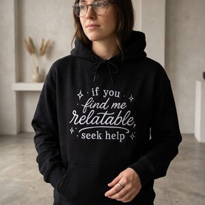 Pu&ograve; includere: Una felpa nera con cappuccio caratterizzata da una scritta ricamata in bianco "if you find me relatable, seek help" circondata da piccole icone a forma di stella. Il capo presenta un cappuccio con coulisse, maniche lunghe e tasca a marsupio.