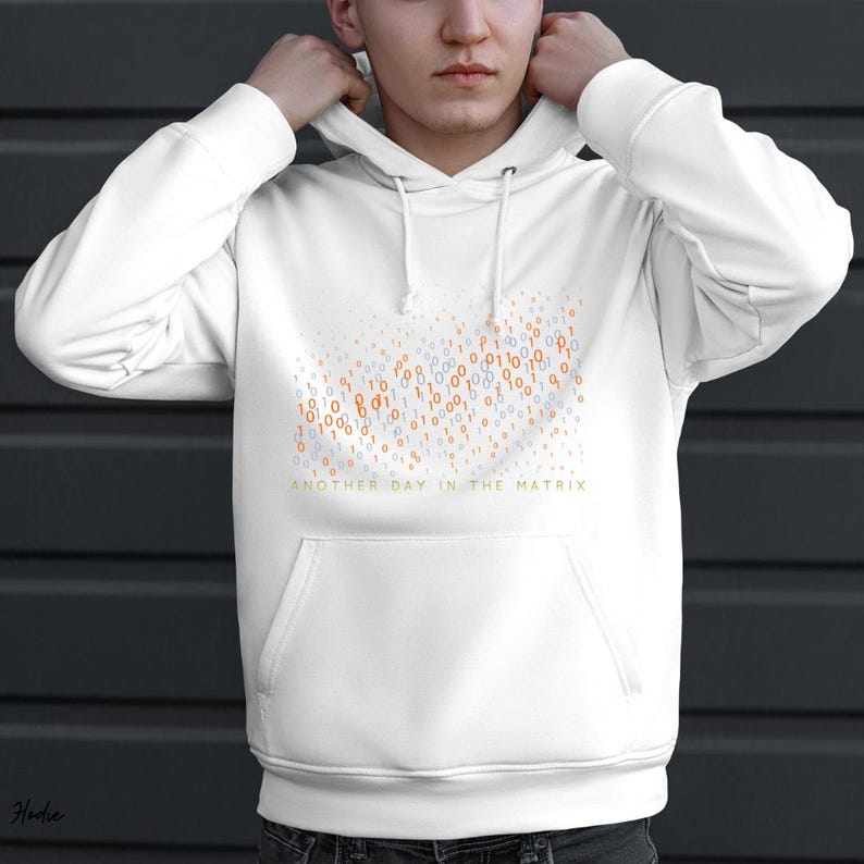 May include: White hoodie with a front pocket and drawstring hood. The design features a pattern of orange, blue, and white binary code numbers, with the text "ANOTHER DAY IN THE MATRIX" in gold.