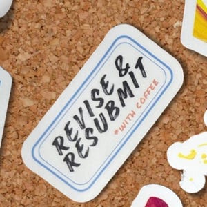May include: A white sticker with a blue border and the words "REVISE & RESUBMIT" in black, with "*WITH COFFEE" below. The sticker is on a corkboard surface.