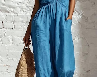 May include: A bright blue jumpsuit featuring a deep V-neckline, short flutter sleeves, and an elasticized waist with side pockets. The garment has a relaxed, wide-leg fit and is paired with a woven straw handbag and brown strappy sandals.