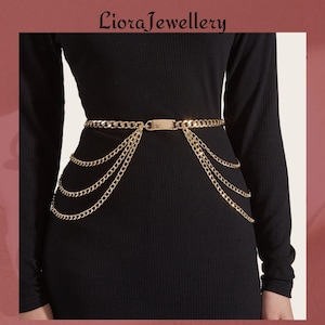 May include: Gold-tone chain belt with multiple dangling chains. The belt features a rectangular clasp and is worn over a black dress. The jewelry is from Liora Jewellery.