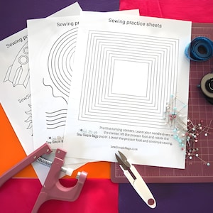 Könnte beinhalten: Eine Sammlung von Nähübungsblättern mit geometrischen Mustern, ein Rollschneider, ein Maßband, Stecknadeln und eine rosa Presse. Die Blätter tragen die Aufschrift "Sewing practice sheets" und "SewSimpleBags.com".
