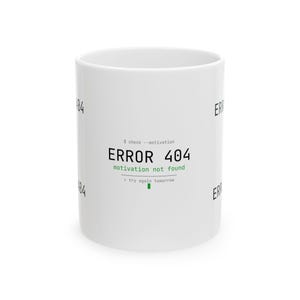 May include: White ceramic mug with the text "ERROR 404 motivation not found" in black and green. The mug also has the text "try again tomorrow". The mug is a cylindrical shape.