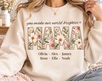 May include: A cream-colored crewneck sweatshirt featuring the text you make our world brighter and the word MAMA in large block letters filled with a floral pattern of pink and white flowers and green leaves, with the names Olivia, Alex, James, Rose, Ella, and Noah printed below.