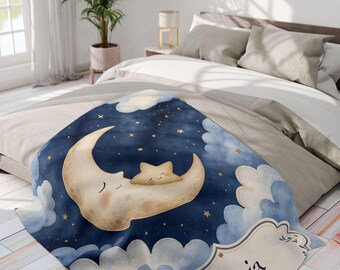 May include: A soft throw blanket featuring a dark blue night sky with a large cream-colored crescent moon and a small star resting on it. The design includes fluffy light blue clouds, scattered gold stars, and a name tag with the name Livia.