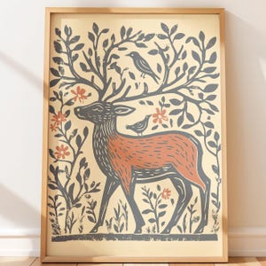 May include: A framed wall art print featuring a stylized deer with large antlers that form tree branches. The deer has a rust-colored body and dark gray outlines. Small birds are perched on the antlers and back, surrounded by gray foliage and orange flowers on a cream background.