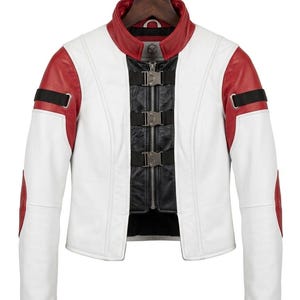 May include: White and red leather jacket with a black panel and silver buckles. The jacket has a red collar and red accents on the shoulders and elbows. The jacket is hanging on a wooden hanger.