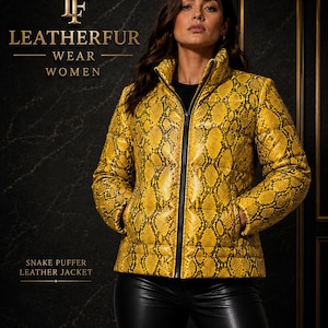Pode incluir: Um casaco acolchoado com estampa de pele de cobra amarela e preta, com gola alta e zíper central preto. O texto LEATHERFUR WEAR WOMEN e SNAKE PUFFER LEATHER JACKET é visível. O casaco apresenta uma textura acolchoada e mangas compridas.
