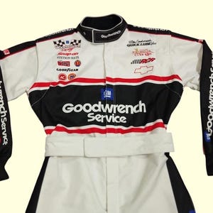 May include: White racing suit with black and red accents. Features the "Goodwrench Service" logo across the chest and sleeves, along with sponsor logos like "Snap-on", "Stetson Hats", and "Goodyear". Includes a Chevrolet logo.