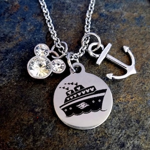 May include: A silver necklace with a charm of a cruise ship with Mickey Mouse heads on it, a charm of a Mickey Mouse head with rhinestones, and a charm of an anchor.