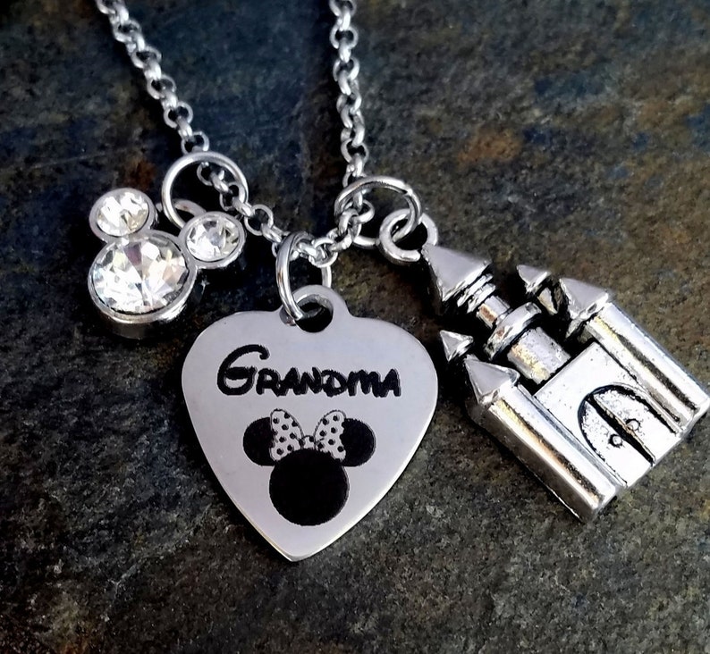 Pu&ograve; includere: Una collana d'argento con un ciondolo a forma di cuore che dice "Nonna" e ha un'immagine in bianco e nero di Minnie Mouse. La collana ha anche un ciondolo d'argento di un castello e un ciondolo di Mickey Mouse di cristallo.