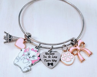 May include: A silver charm bracelet with a pink heart, a paw print charm, a pink bow charm, a silver Eiffel Tower charm, and a silver charm with a white cat and the text "Because I'm a Lap Cat That's Why".