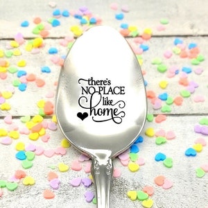 May include: A silver spoon with the phrase "there's NO PLACE like home" engraved on it. The spoon is surrounded by colorful heart-shaped sprinkles.