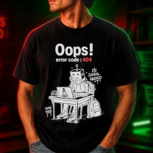 May include: Black t-shirt with a graphic of a robot at a desk with a laptop. The text "Oops! error code: 404" is above the robot. A backpack and the words "School Hacked" are also visible. The words "Game Over" are at the bottom left.