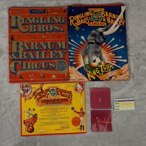 Peut inclure: Collection de souvenirs vintage du cirque Ringling Bros. et Barnum & Bailey. Comprend trois boîtes colorées et un certificat de présence. Les boîtes présentent des artistes de cirque et un éléphant. Le certificat est jaune avec des accents rouges et bleus.