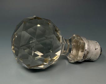 Remate de lámpara vintage de cristal facetado con bola redonda transparente y base plateada.