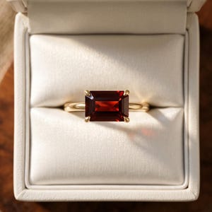 Unik öst-västlig smaragdslipad granatring, horisontell solitär i gult guld, minimalistisk födelsesten i januari.