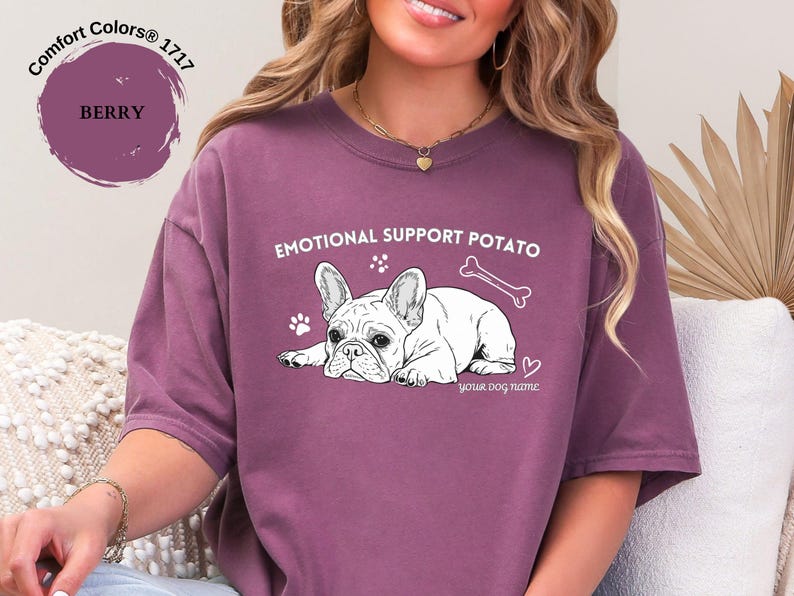 May include: Berry-coloured t-shirt featuring a French Bulldog graphic with the text "EMOTIONAL SUPPORT POTATO". The design includes a bone, paw prints, and a heart. The text "your dog name" is below the dog.