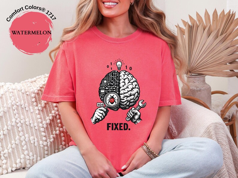 May include: A watermelon-colored t-shirt featuring a graphic of a split brain. One side shows a circuit board pattern with a magnifying glass over a red bug, while the other side shows a biological brain. The text 404 and FIXED are printed below.