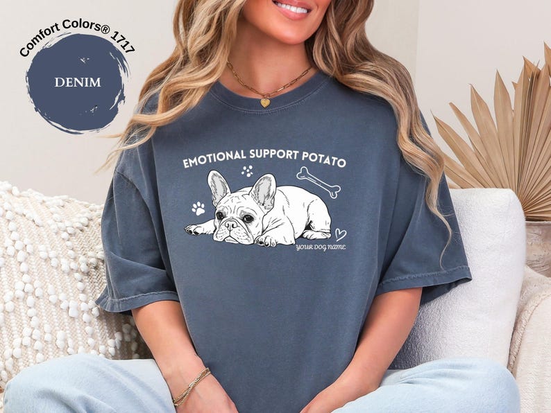 May include: Denim blue t-shirt featuring a French Bulldog graphic and the text "EMOTIONAL SUPPORT POTATO". The design includes a bone, paw prints, and a heart. The shirt is a Comfort Colors 1717.