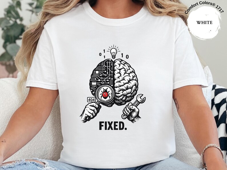 May include: A white t-shirt featuring a graphic of a brain split into a circuit board and organic side. One hand holds a magnifying glass over a red bug with a 404 label, while the other holds a wrench. Above is a lightbulb and binary code, with the text FIXED.