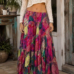 May include: A long, tiered maxi skirt featuring a vibrant patchwork pattern in shades of magenta, purple, teal, and lime green. The skirt has an elasticized waistband with a drawstring tie and a full, flowing silhouette that reaches the ankles.