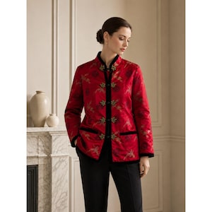 May include: A red satin jacket featuring a mandarin collar, long sleeves, and black velvet trim along the front opening and pockets. The fabric is decorated with an intricate gold and dark red floral pattern and secured with five black frog closures.