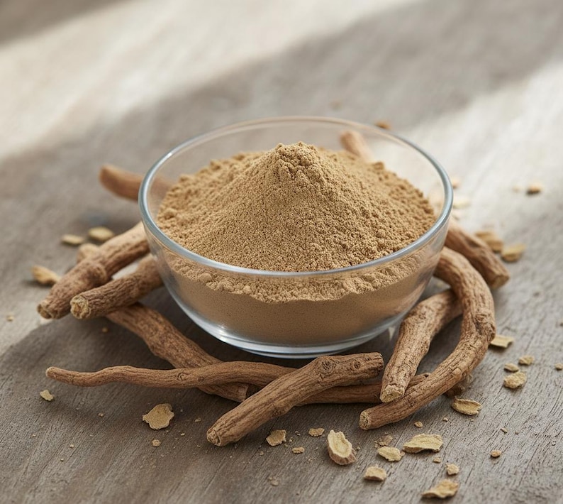 May include: A clear glass bowl filled with light brown powder, surrounded by several pieces of dried, brown root. The bowl sits on a wooden surface, with small pieces of the root scattered around.