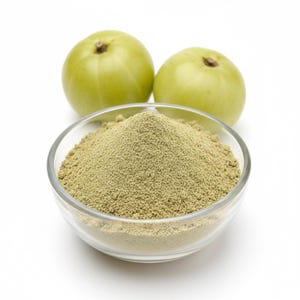 Puede incluir: Un cuenco de vidrio transparente lleno de polvo verde claro, con dos frutas verdes en el fondo. Las frutas son redondas y tienen un pequeño tallo. El polvo parece finamente molido.