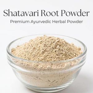 Może przedstawiać: Przezroczysta szklana miska wypełniona jasno brązowym proszkiem z korzenia Shatavari. Tekst nad miską brzmi "Shatavari Root Powder" i "Premium Ayurvedic Herbal Powder". Proszek ma drobną, ziarnistą konsystencję.