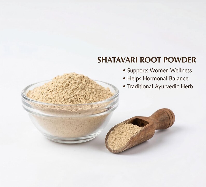 Może przedstawiać: Przezroczysta szklana miska wypełniona jasno brązowym proszkiem z korzenia Shatavari. Obok miski leży drewniana miarka z proszkiem. Tekst: Shatavari Root Powder, Wspiera dobre samopoczucie kobiet, Pomaga w r&oacute;wnowadze hormonalnej.