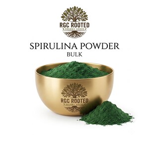 Könnte beinhalten: Eine goldfarbene Metallschale gefüllt mit dunkelgrünem Spirulina-Pulver, begleitet von einem kleinen Haufen desselben Pulvers. Die Schale zeigt das Baum-Logo von RGC ROOTED ORGANIC GOODS. Der Text darüber lautet RGC ROOTED ORGANIC GOODS, SPIRULINA POWDER, BULK.