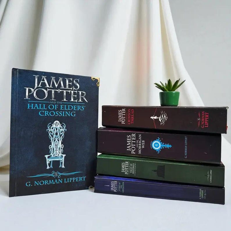 May include: A collection of five hardcover books by G. Norman Lippert. One book stands upright, titled James Potter and the Hall of Elders' Crossing, while four others are stacked horizontally. A small green succulent in a pot sits on the stack.