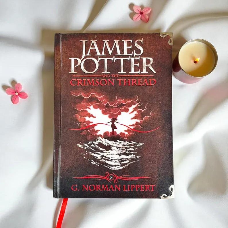 May include: A hardcover book titled James Potter and the Crimson Thread by G. Norman Lippert, featuring a dark brown cover with a central illustration of a figure against red clouds and waves, accented by silver metal corner protectors.