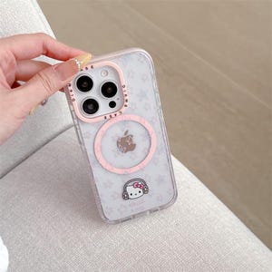 K&ouml;nnte beinhalten: Transparente iPhone-H&uuml;lle mit rosa Kameraring und rosa Kreis mit Apfel-Logo. Die H&uuml;lle hat ein Muster aus kleinen wei&szlig;en Sternen und eine Hello Kitty-Grafik.