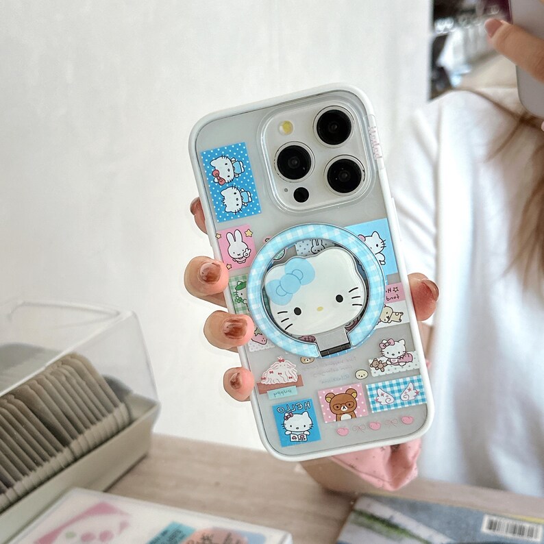Puede incluir: Funda transparente para tel&eacute;fono con dise&ntilde;o de Hello Kitty. La funda presenta un soporte de anillo azul con una cara de Hello Kitty y varias pegatinas de personajes de dibujos animados. La funda est&aacute; dise&ntilde;ada para un tel&eacute;fono inteligente.
