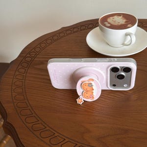 May include: A white ceramic mug with a black handle and the text "But First, Coffee" in a handwritten style. The mug is on a white surface. The mug is 10 cm tall.
