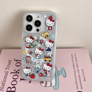 May include: Clear phone case featuring a colorful Hello Kitty design. The case has multiple illustrations of Hello Kitty in various poses, along with flowers, stars, and other cute elements. The word "KITTY" is printed at the bottom.