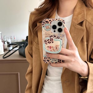 May include: Clear phone case with a leopard print design and a pop-up grip featuring a Hello Kitty design. The case has a clear background with a cartoon design and the text "YTTIK".