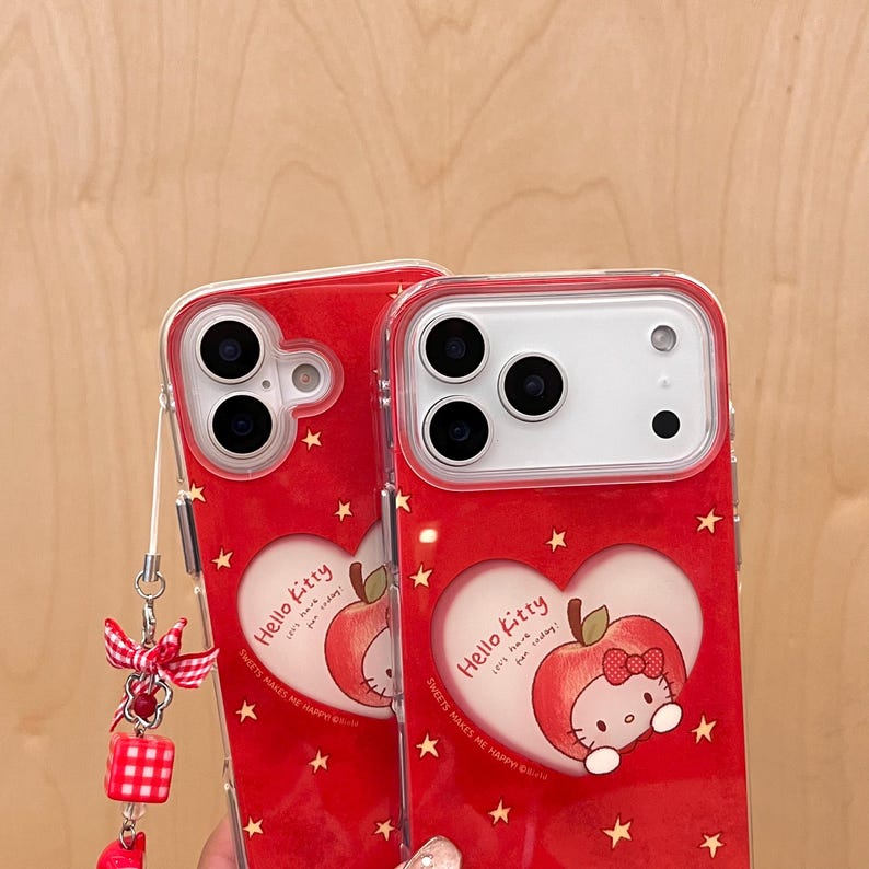 Puede incluir: Dos fundas rojas para tel&eacute;fono con un dise&ntilde;o de Hello Kitty. Cada funda presenta un recorte en forma de coraz&oacute;n con una manzana y un gr&aacute;fico de Hello Kitty. Las fundas tienen un patr&oacute;n de estrellas y el texto "Hello Kitty" y "Sweets makes me happy".
