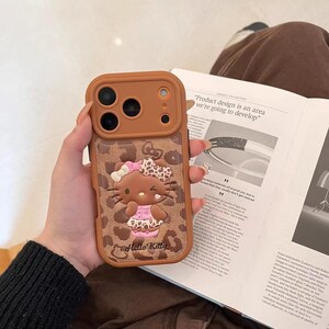 Läderfodral i rosa brunt leopardmönster med Hello Kitty-motiv och snodd för iPhone 17 Pro, 16 Pro Max och 15-serien. Only phone case