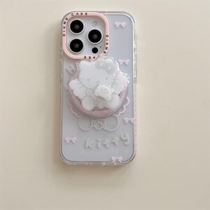 K&ouml;nnte beinhalten: Transparente Handyh&uuml;lle mit einem rosa-wei&szlig;en Hello Kitty-Design. Die H&uuml;lle verf&uuml;gt &uuml;ber einen rosa Ringhalter mit einer Hello Kitty-Figur und dem Wort "kitty" in Wei&szlig;. Kleine rosa Schleifen sind &uuml;ber die H&uuml;lle verstreut.