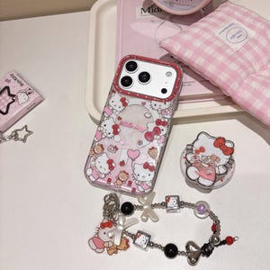 May include: A selection of Hello Kitty themed items, including a phone case, pop socket, bracelet, and small box. The phone case has a red border and is decorated with Hello Kitty motifs. The bracelet features black beads and silver charms.